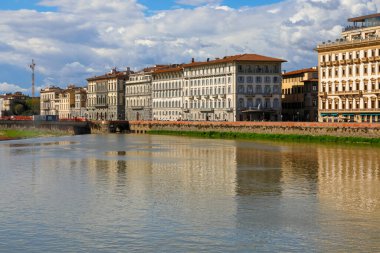 Florence, İtalya - 15 Nisan 2023: Oteller de dahil olmak üzere tarihi binalar burada Arno Nehri kıyıları boyunca görülebilir. Güneşli bir gün ve mavi gökyüzünde bulutlar var.