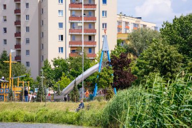 Varşova, Polonya - 28 Haziran 2023: yanında oyun alanı olan bir apartman. Hemen yanında Praga Poludnie bölgesinde bir parkın parçası olan Goclaw malikanesi var.