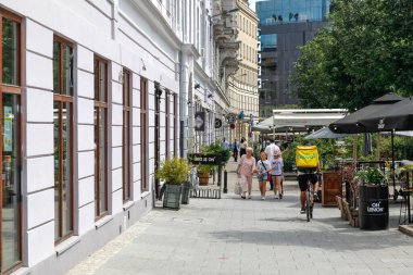 Varşova, Polonya - 19 Temmuz 2023: İnsanların yürüdüğü kaldırım binalar boyunca. Açık hava restoranının şemsiyeleri Five Corners Meydanı yakınlarında görülebilir.