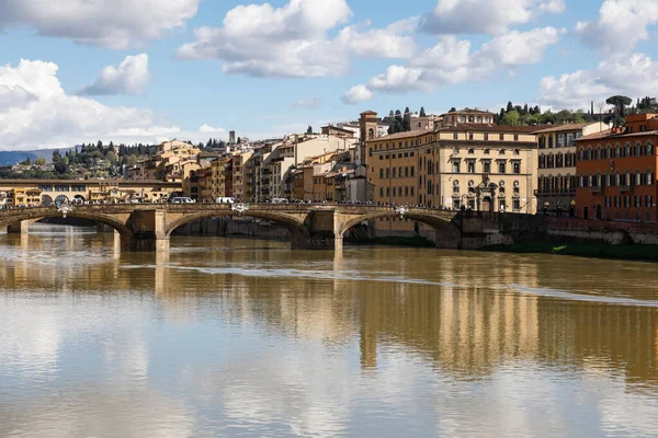 Florence, İtalya - 15 Nisan 2023: Arno nehri kıyısındaki konut binaları ve iki köprü. Uzakta, bir çok insan hücrede görülebilir.