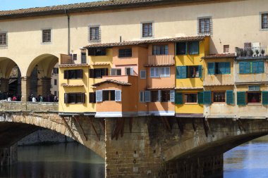 Florence, İtalya - 15 Nisan 2023: Arno Nehri boyunca uzanan ikonik Ponte Vecchio (Eski Köprü) 'nun bir parçası. Uzaktaki köprüde bir grup insan görülebilir.