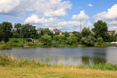 Varşova, Polonya - 21 Temmuz 2023: Göl parkı Praga Poludnie bölgesindeki Goclaw konutlarının önemli bir parçasıdır. Uzaklarda, gölün diğer tarafında, insanları görebilirsin.