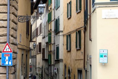 Florence, İtalya - 15 Nisan 2023: Eski kasabadaki apartmanlar dar sokağın her iki tarafındadır. Bu binaların pencerelerinde kepenkler vardı.
