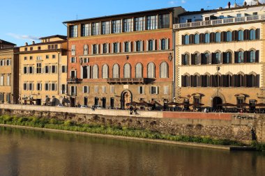 Floransa, İtalya - 16 Nisan 2023: Arno Nehri kıyıları tarafından burada görülen şehir manzarası var. Buradaki binalar yavaşça batan güneşin ışınlarıyla aydınlatılıyor.