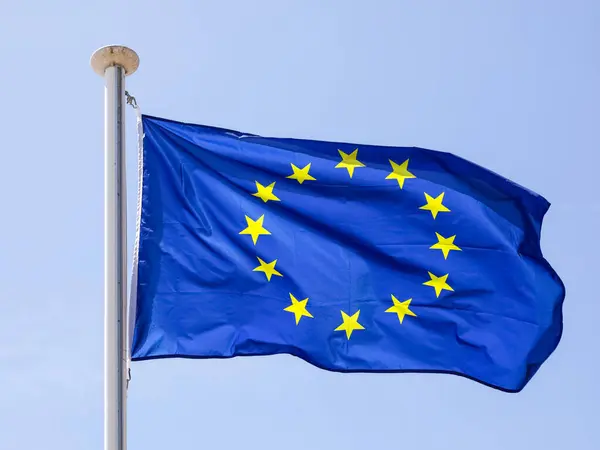 stock image Blue flag of Europe with its circle of yellow stars blows with the wind