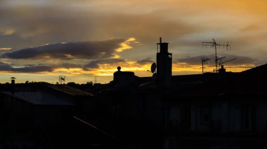 Yaz günbatımının manzarası. Gökyüzü, bacalı ve çeşitli antenli evlerin çatılarının silueti üzerinde. Fransa 'nın Nice şehrinin renkli günbatımı gökyüzü