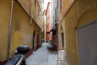 Nice, Fransa - 27 Nisan 2023: Şehrin eski kesiminde dar bir yaya sokağı uzun kasaba evleri arasında uzanır.