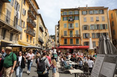 Güzel, Fransa - 27 Nisan 2023: binalar ve eski kasabada güneşli bir günde görülen küçük bir meydan. Çok fazla yaya trafiği var ve meydanda da açık kafeler var..