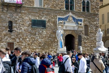 Floransa, İtalya - 14 Nisan 2023: Piazza della Signoria 'daki Palazzo Vecchio cephesi. David 'in heykelinin bir kopyası var. Birçok insan buradaki şehri gezer.