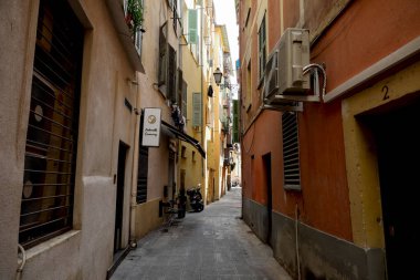 Güzel, Fransa - 27 Nisan 2023: Dar cadde, eski kasabadaki uzun konakların cephelerinin gölgesinde güneşten gizlenmiş gibi..