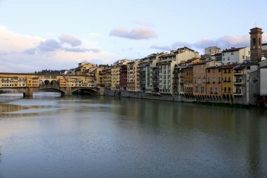 Floransa, İtalya - 13 Nisan 2023: Arno Nehri 'nin kıyısında, şehrin içinden akan çeşitli tarihi binalar vardır. Ponte Vecchio uzaktan görülebiliyor