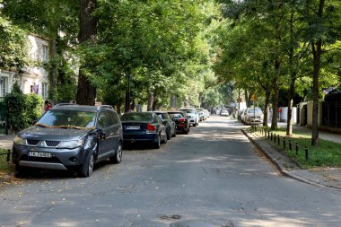 Varşova, Polonya - 13 Eylül 2023: iki tarafında ağaçlar ve bir tarafında arabaların park edildiği dar bir cadde. Burası Saska Kepa konutları, Praga-Poludnie bölgesinin bir parçası..