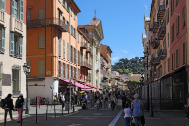 Güzel, Fransa - 25 Nisan 2023: güneşli bir günde eski bir kasabada yaya sokağı. Birçok insan binaların gölgesinde bu cadde boyunca yürür..