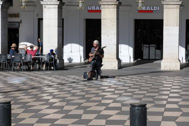 Güzel, Fransa - 2 Mayıs 2023: Sandalyede oturan yalnız bir müzisyen, yakınlardaki insanlara gitar çalarak müzik yapıyor. Bu gösteri oyun salonlarının yakınındaki Place Massena 'da gerçekleştirilecek..