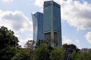 Varşova, Polonya - 1 Eylül 2023: Şehrin kalbinde iki modern gökdelen güneşli ve hafif bulutlu bir gökyüzüne karşı görülür