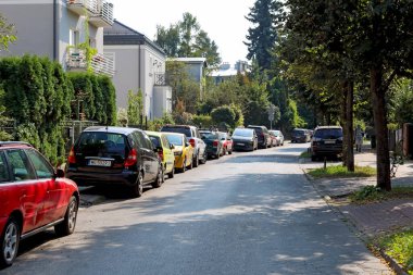 Varşova, Polonya - 13 Eylül 2023: Praga-Poludnie semtindeki Saska Kepa konutlarının bitişiğindeki evlerin yanında kısmen yolda ve kısmen kaldırımda park etmiş bir sıra araba görülebilir