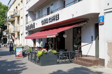 Varşova, Polonya - 12 Eylül 2023 Saska Kepa konutlarındaki bir iskan binasının cephesinin hemen yanında tanınmış bir ağa ait bir sokak kafesi var.