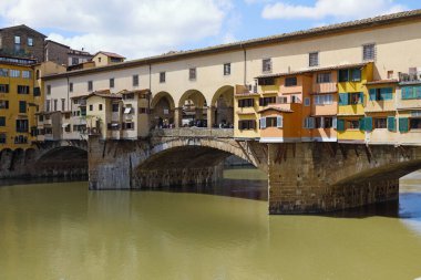 Floransa, İtalya - 15 Nisan 2023: Arno Nehri 'ni geçen ortaçağ ikonik köprüsü Ponte Vecchio' nun kısmi manzarası. Uzakta bir grup insanı köprüde görebilirsiniz..