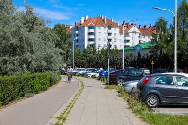 Varşova, Polonya - 22 Ağustos 2023: Praga-Poludnie semtindeki Goclaw konutlarında görüldüğü gibi bir apartman bloğu, kaldırımın yanında bir bisiklet yolu, park edilmiş arabalar ve doğa..