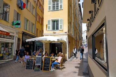 Güzel, Fransa - 27 Nisan 2023: dar geçitler arasında dar bir apartman evinin yanında açık hava restoranı var. Bu restorandaki koltuklar zaten lokantalar tarafından tutuldu..