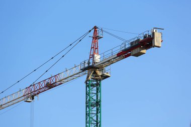 İnşaat alanının yukarısında, mavi gökyüzüne karşı, endüstriyel bir makinenin üst kısmını görebilirsiniz, yüksek bir kule vinci. Varşova 'daki Goclaw konutlarında inşaat devam ediyor.