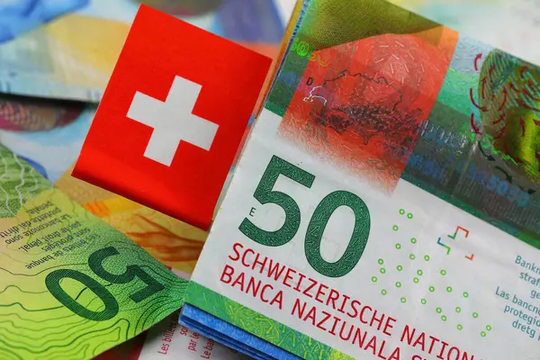 Swiss franc banknotes in different denominations and Swiss flag. CHF paper money, the introduction of these banknotes was released from April 2016 to 2019.