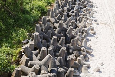 Kum tepelerini fırtınalı havalarda meydana gelen tehlikeli deniz dalgalarından korumak için yerleştirilmiş devasa bir yığın beton tetrapod. Ustronie-Morskie, Polan 'da bir plajın kenarında.