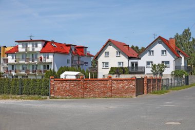 Ustronie Morskie, Polonya - 22 Mayıs 2024: Yolun ötesinde ve kırmızı tuğlalı evler, güneşli bir günde bu tatil köyünde görüldüğü gibi