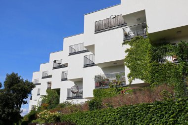 Warsaw, Poland - September 24, 2023: A modern building with a white facade and balconies surrounded by nature as part of the Goclaw housing estate in the Praga-Poludnie district clipart