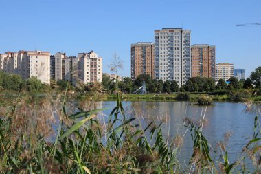 Varşova, Polonya - 5 Eylül 2023: Praga-Poludnie bölgesindeki Goclaw konutlarının genel manzarası, gölü olan bir parkın arkasındaki bloklar.