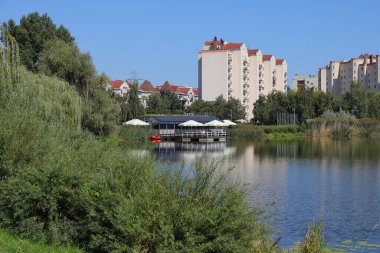 Varşova, Polonya - 5 Eylül 2023: Praga-Poludnie bölgesindeki Goclaw konutlarının genel manzarası, gölü olan bir parkın arkasındaki bloklar