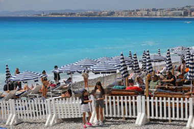 Nice, Fransa - 25 Nisan 2023: plajlar Akdeniz kıyısındaki şehrin güney ucunda yer almaktadır. Burası insanların plajda şezlonglar ve plaj şemsiyeleriyle dinlendikleri bir yer.