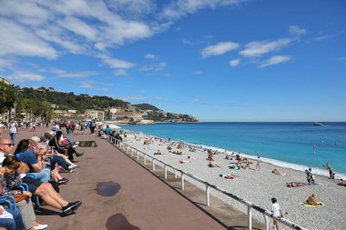 Nice, Fransa - 2 Mayıs 2023: Deniz kenarındaki gezinti güvertesi ve plajlar Akdeniz kıyısındaki şehrin güney ucunda yer almaktadır. İnsanların hem gezinti güvertesinde hem de plajda dinlendikleri bir yer..