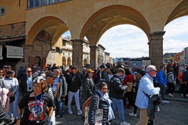 Florence, İtalya - 15 Nisan 2023: Arno nehri üzerindeki ünlü ortaçağ Ponte Vecchio 'su gezintiler ve gezintiler için popüler bir yerdir. Hücrede yürüyen kalabalıkları görebilirsin.