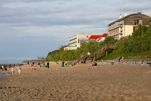 stock image Ustronie Morskie, Poland - May 23, 2024: The sandy beach of the Baltic Sea and the wooden stairs connecting it to the village area and some buildings in the light of the evening sun.