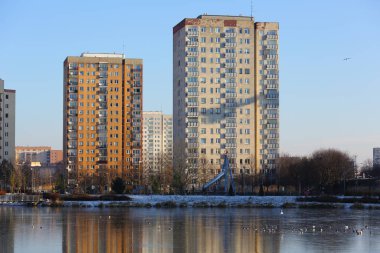 Varşova, Polonya - 8 Ocak 2024: Praga-Poludnie bölgesindeki Goclaw konutlarında donmakta olan bir gölün arkasındaki uzun apartman blokları
