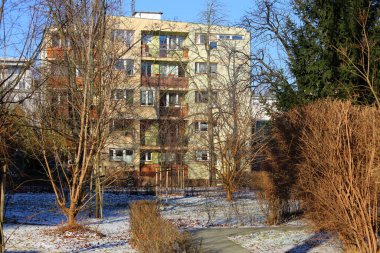 Varşova, Polonya - 9 Ocak 2024: Güneşli bir günde Praga-Poludnie bölgesinin Saska Kepa bölgesinde yapraksız ağaçların arkasındaki apartmanlar