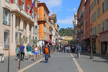 Güzel, Fransa - 2 Mayıs 2023: güneşli bir günde eski kasaba yaya sokağı. Birçok insan bu caddede güneşin altında ya da kısmen binaların gölgesinde yürür.