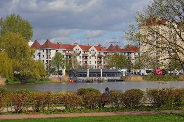 Varşova, Polonya - 6 Nisan 2024: Praga-Poludnie bölgesinin Goclaw bölgesinde çok katmanlı binaların yakınında bir göl bulunan kamu parkı