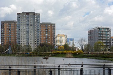 Varşova, Polonya - 6 Nisan 2024: Göl üzerindeki bulutlar, Praga-Poludnie 'nin Goclaw semtindeki apartman bloklarının yakınındaki bir kamu parkı.