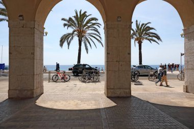 Nice, Fransa - 28 Nisan 2023: Eski kasabadan sahil şeridine uzanan, palmiye ağaçlarının yetiştiği, insanların yürüdüğü ve arabaların sürdüğü gölgeli oyun salonunun manzarası