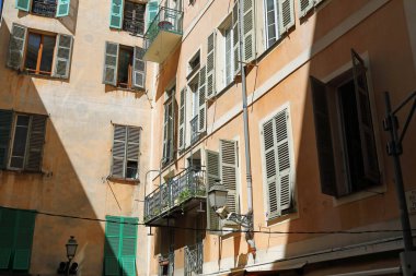 Güzel, Fransa - 24 Nisan 2023: eski şehir evlerinin cephesi. Pencereler güneşten korunan daireleri gölgelemek için ahşap panjurlarla donatılmış..