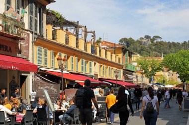 Nice, Fransa - 21 Nisan 2023: Açık hava restoranları ve Cours Saleya olarak bilinen ünlü pazar meydanına doğru yürüyen insanlar