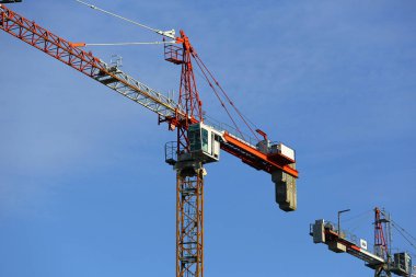 Warsaw, Poland - January 30, 2024: Two cranes working on a construction site can be seen against a blue sky in the Goclaw housing estate in the Praga-Poludnie district clipart