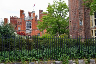 Londra, İngiltere, İngiltere - 7 Haziran 2010: Kökeni 1514 yılına dayanan Hampton Court Palace, bir çitin arkasında kısa bir mesafeden görülebilir. Kraliyet Sarayı.