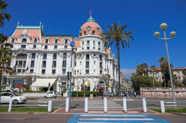 Nice, France - April 26, 2023: A pedestrian crossing that leads across the Promenade des Anglais to the imposing building that houses the legendary Hotel Negresco clipart