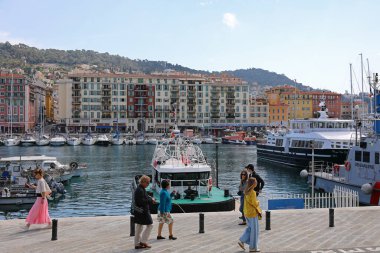 Nice, Fransa - 23 Nisan 2023: Şehrin binaları biraz daha ileride, Lympia Limanı 'nın karşısında görülebilir. Limanda demirlemiş yatlar ve yürüyenler de var..