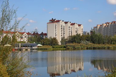 Varşova, Polonya - 21 Eylül 2024: Apartman blokları bir gölün arkasında görülebilir. Praga-Poludnie 'nin bir alt bölgesi olan Goclaw' da güneşli bir gün..