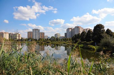 Varşova, Polonya - 21 Eylül 2024: Bir göl arkasında bir apartman bloğu görülebilir. Güneşli bir günde, Praga-Poludnie 'nin bir alt bölgesi olan Goclaw' da gölü olan bir park da görebilirsiniz..