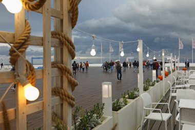 Sopot, Polonya - 13 Ekim 2024: Avrupa 'nın en uzun rıhtımlarından biri. Açık hava kafenin bir kısmı burada görülebilir. İnsanlar bu bulutlu günde yürüyorlar.